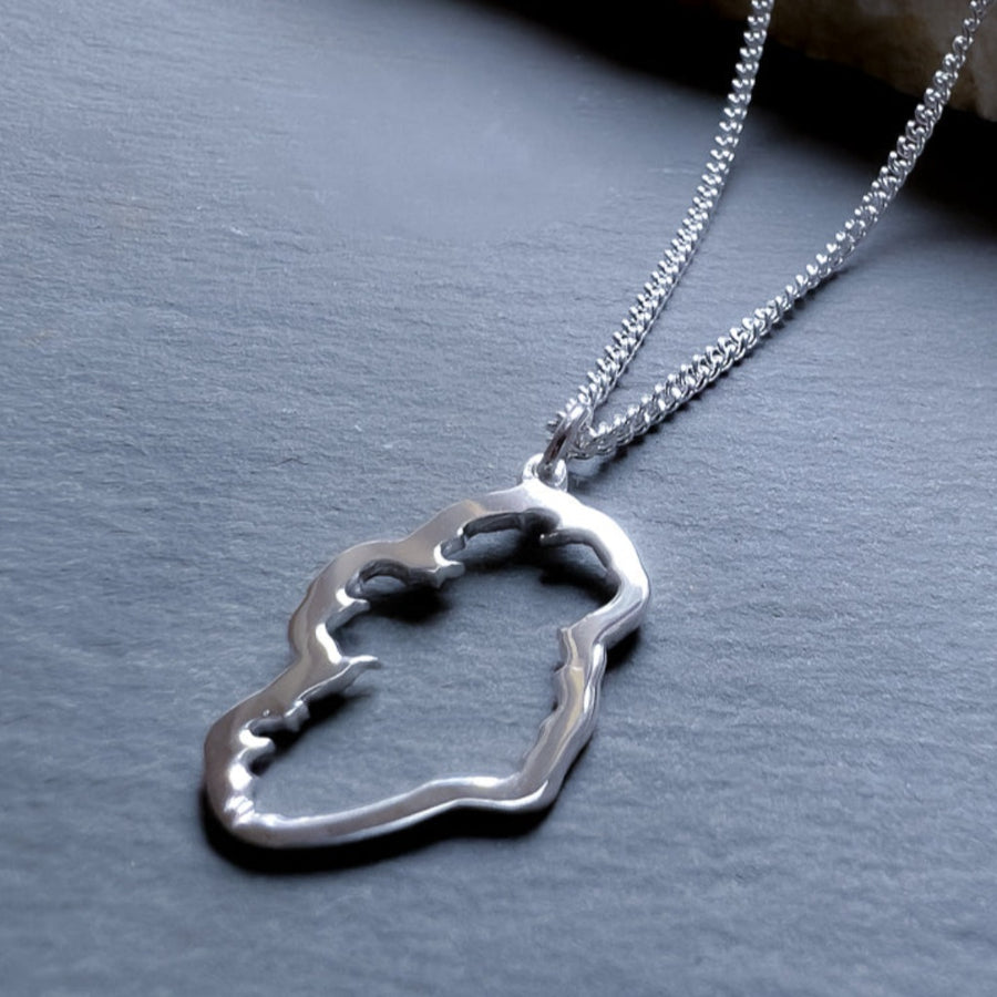a sterling silver men's map of ireland necklace resting on a stone