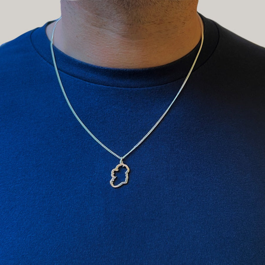 a sterling silver map of ireland necklace on a man's neck