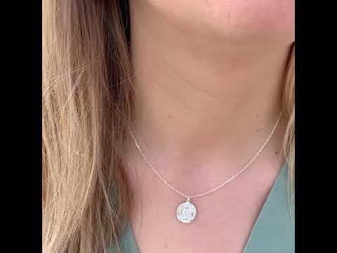 video of a woman wearing a dara knot sterling silver necklace and matching drop earrings with the beach in the background